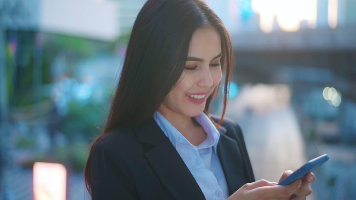 A young business woman wearing black suit is using smart phone , in the city, Business Lifestyle Concept.